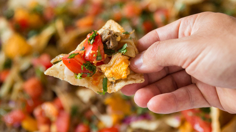 man holding loaded nacho chip