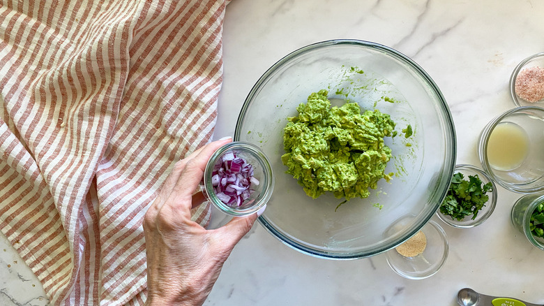 adding red onion to bowl