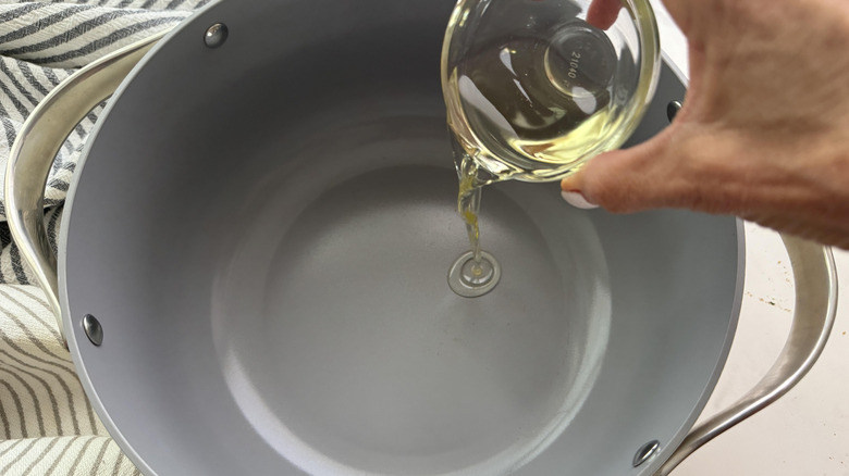 hand adding oil to pan
