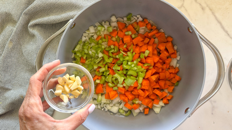 hand adding garlic to pot