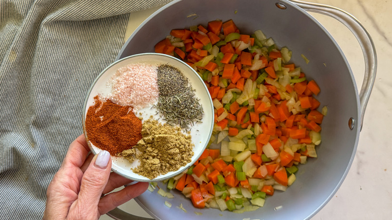 hand adding spices to pot