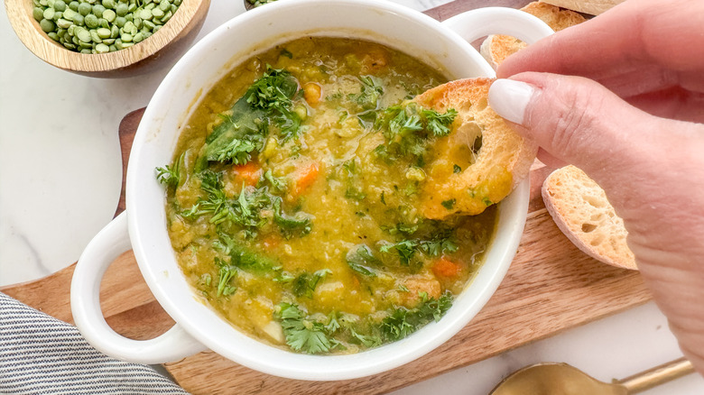 hand dipping bread in soup