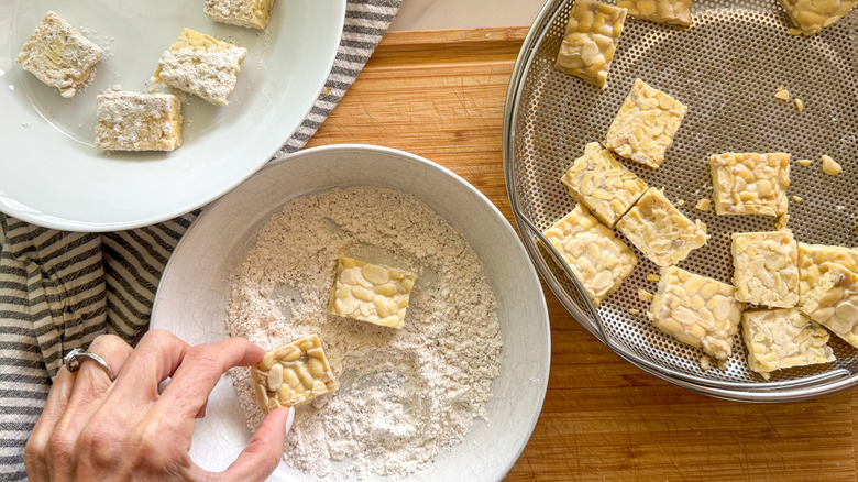 Hand dipping tempeh in breading mixture