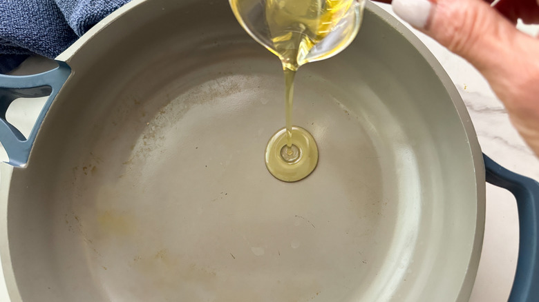 Hand adding oil to a pan