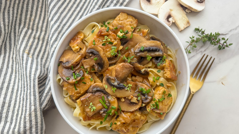 Tempeh Marsala in white bowl next to gold fork