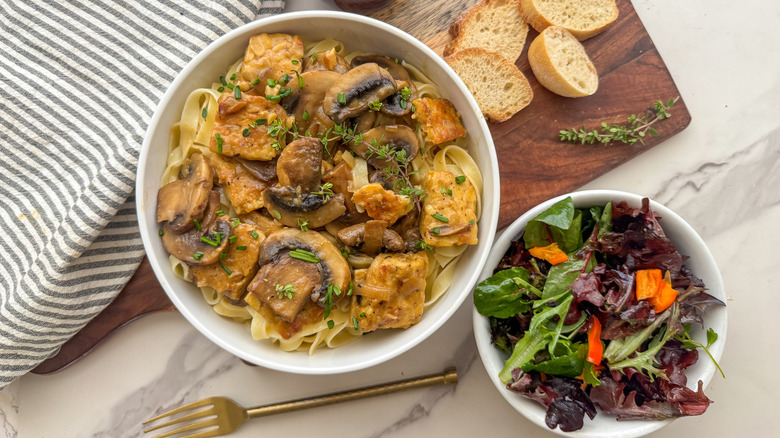 Bowl of tempeh Marsala next to bowl of salad