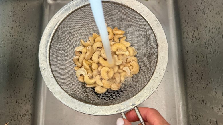 water rinsing cashews in colander