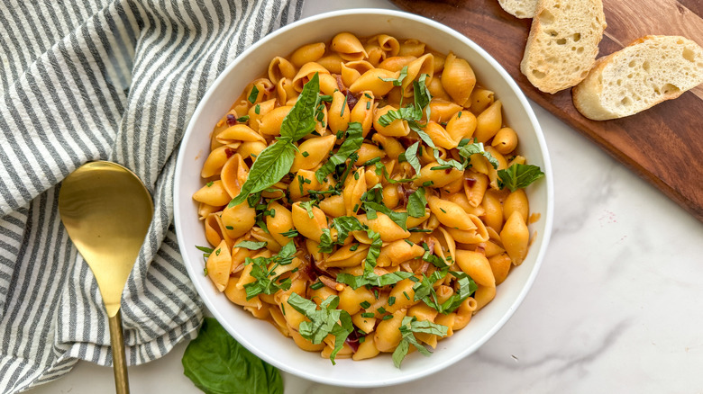 vodka sauce shell pasta served in bowl with basil and bread