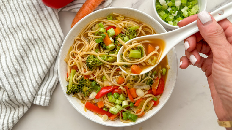 hand holding spoonful of soup