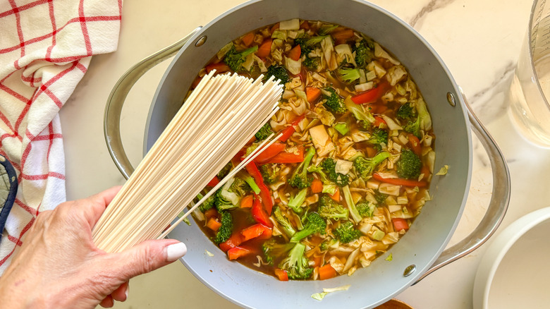 hand adding the noodles