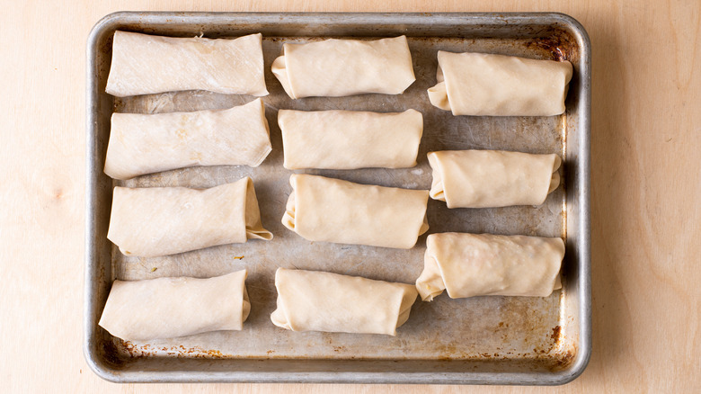 raw egg rolls on a sheet pan