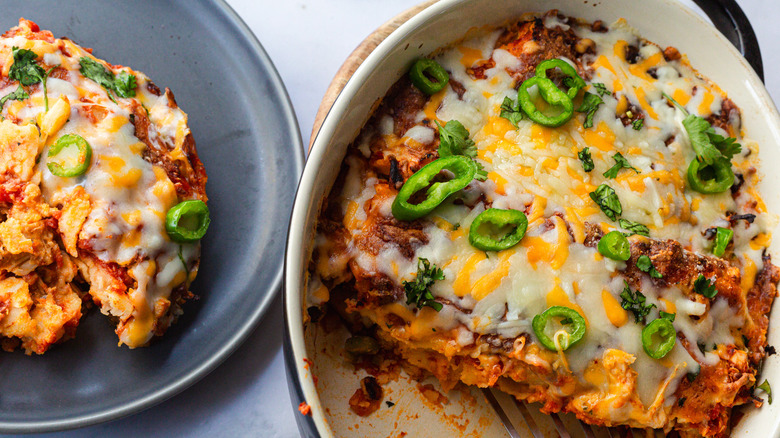 Enchiladas besides bowls of jalapeno and sour cream