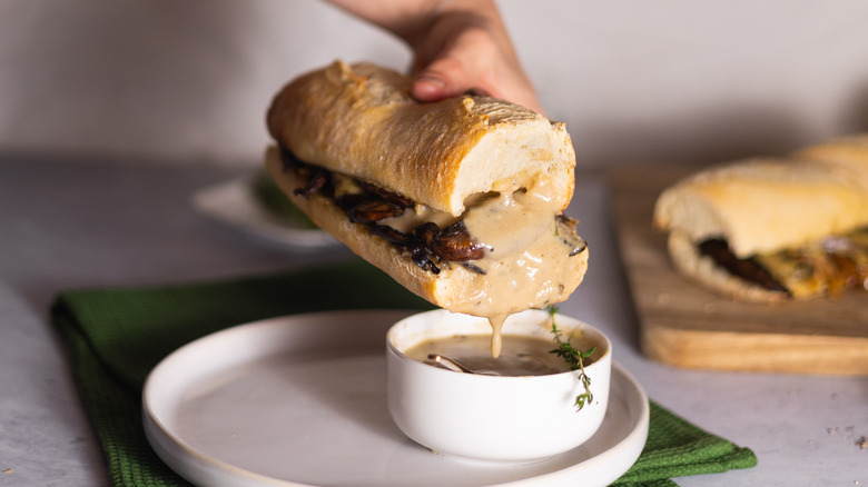 vegetarian french dip sandwich being dipped in jus 