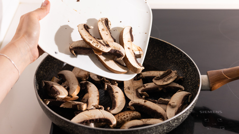 sliced mushrooms going into skillet 