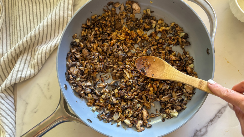 Wooden spoon stirring ingredients in pan