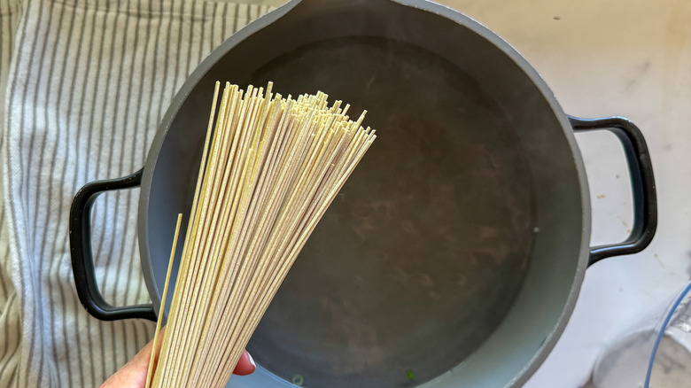 Dry noodles going into pot filled with water