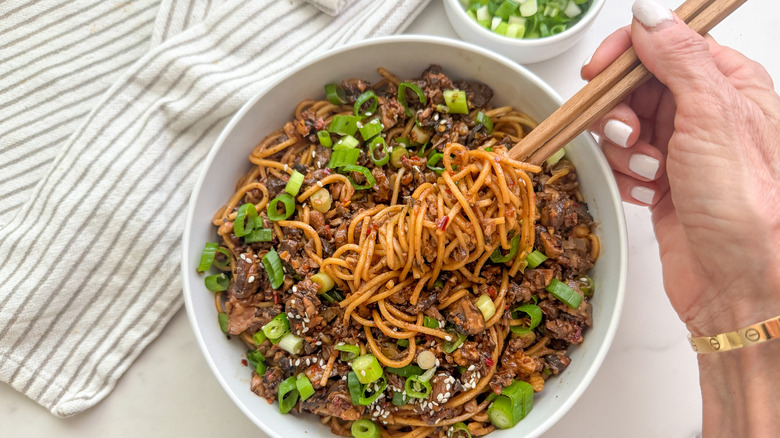 Hand scooping noodles with chopsticks