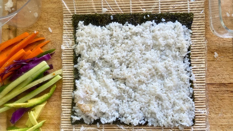 rice layered onto nori sheet and bamboo mat