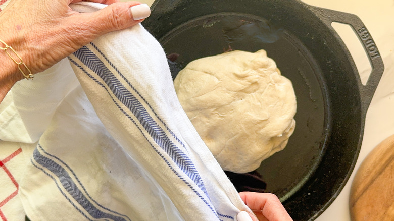 hands covering dough with towel