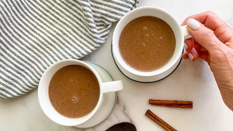 white mug with champurrado with hand