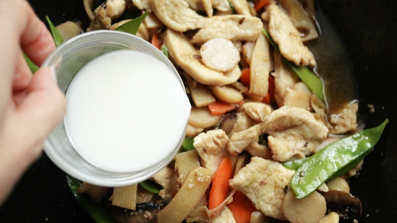 pouring cornstarch slurry on chicken