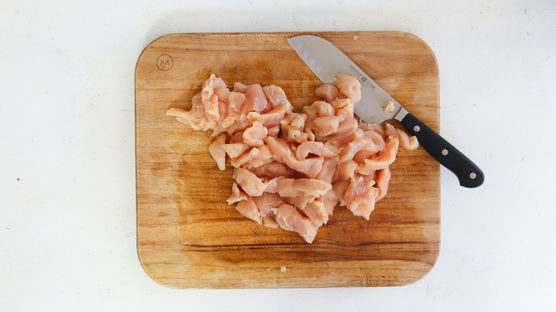 chicken breast on a cutting board with knife