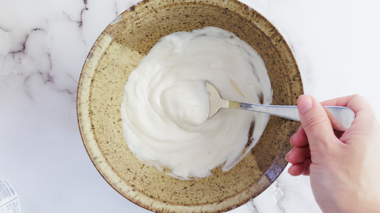 Hand mixing yogurt with sweetener in bowl