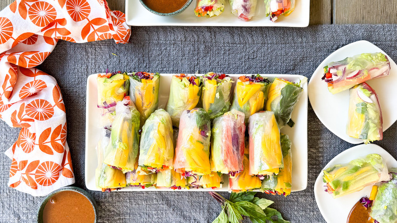 Vibrant rainbow summer rolls on platter and plates