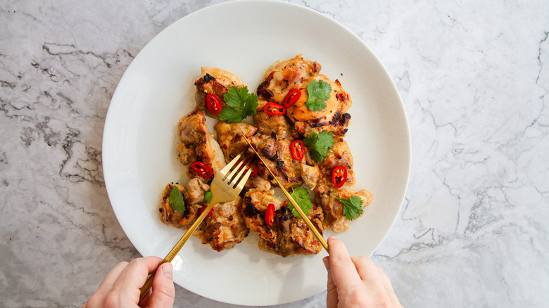 Person with cutlery about to cut into chicken