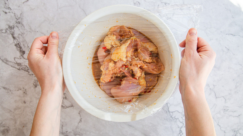 Hands covering bowl with clingfilm