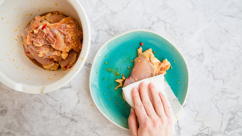 Patting chicken dry with paper towels