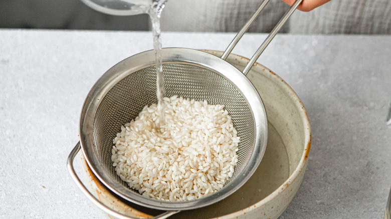 Rinsing rice in a sieve with water