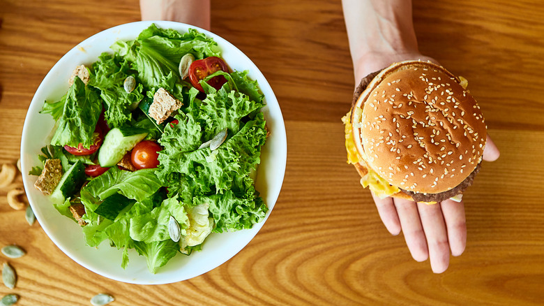 hands holding salad or burger