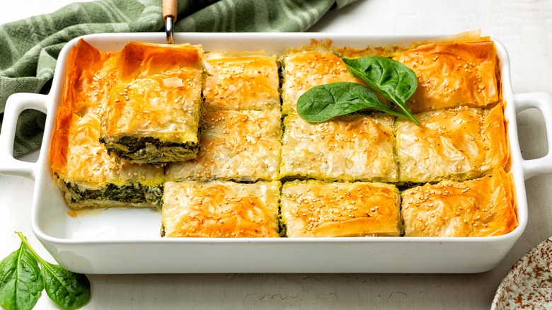 Spanakopita casserole in white dish with basil leaves