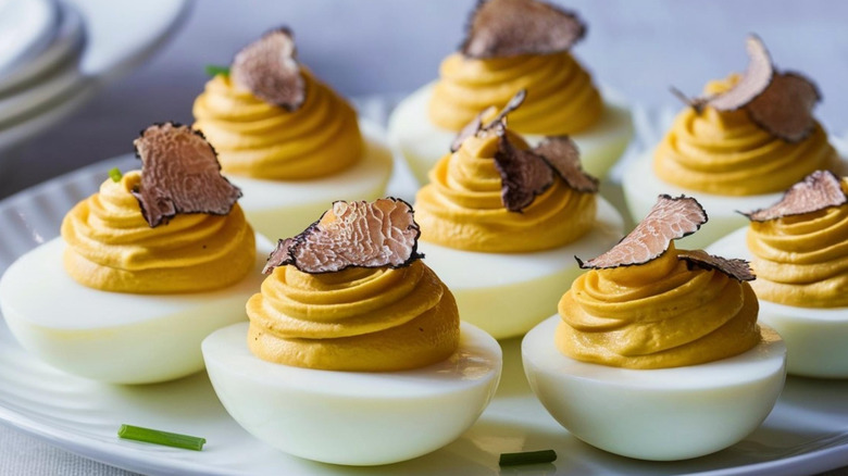 Deviled eggs topped with truffle slices on plate