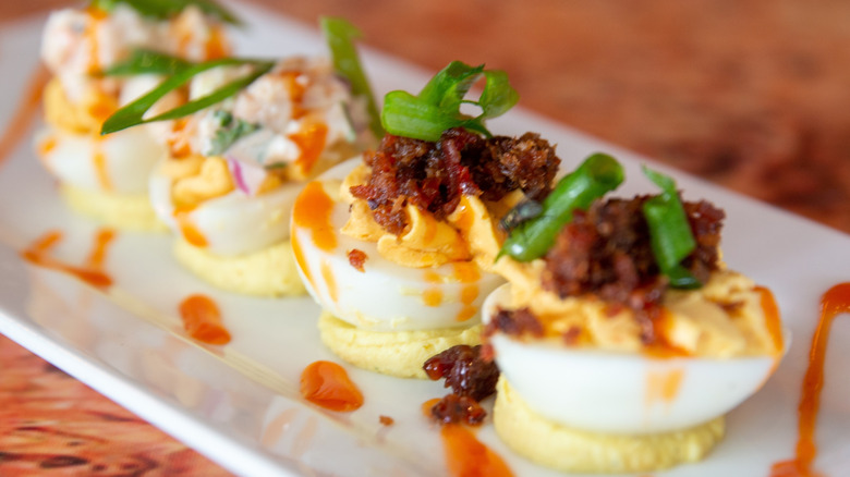 Deviled eggs with elaborate toppings on plate