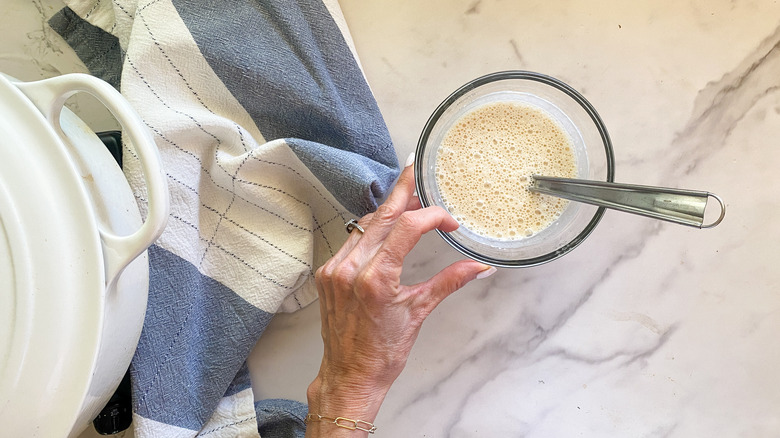 Hand holding glass bowl with milk mixture