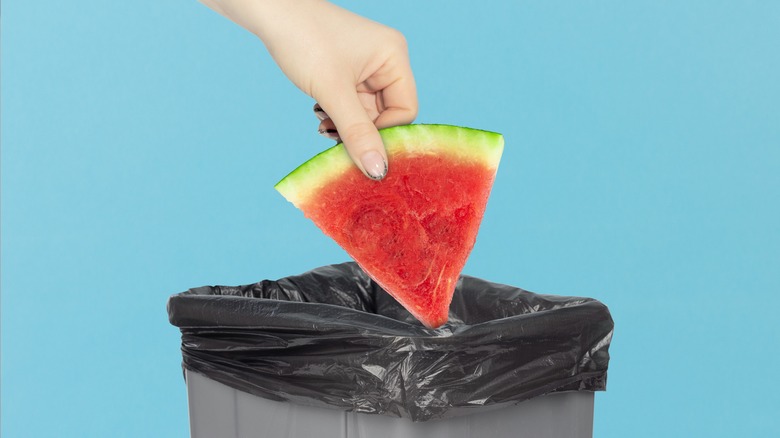 Hand putting slice of watermelon in trash