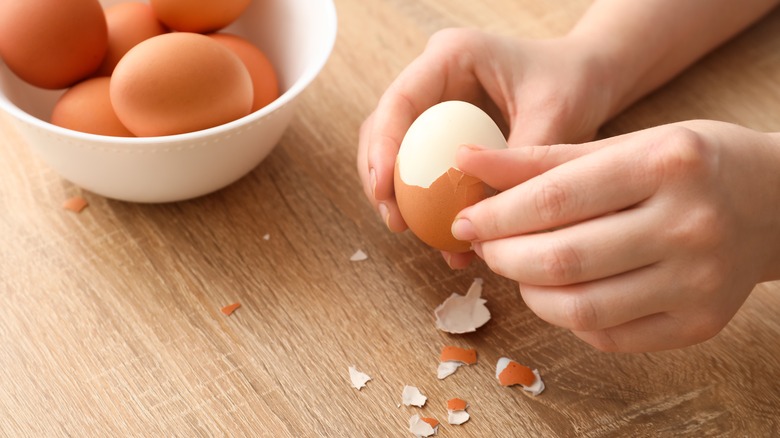 hands peeling hard boiled egg