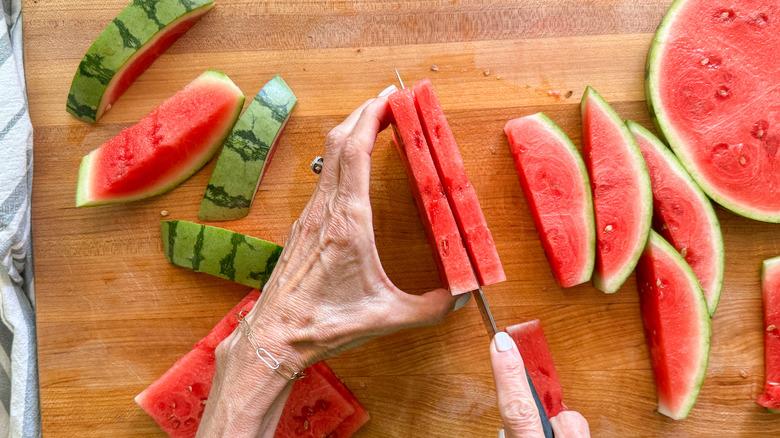 hands cutting watermelon square