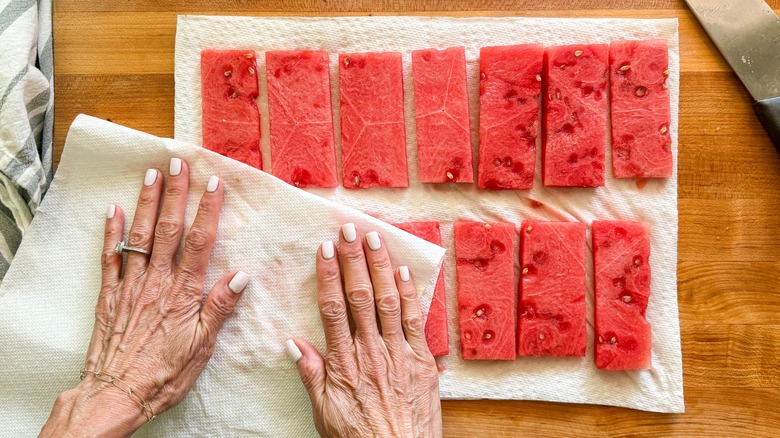 hands drying slices of watermelon