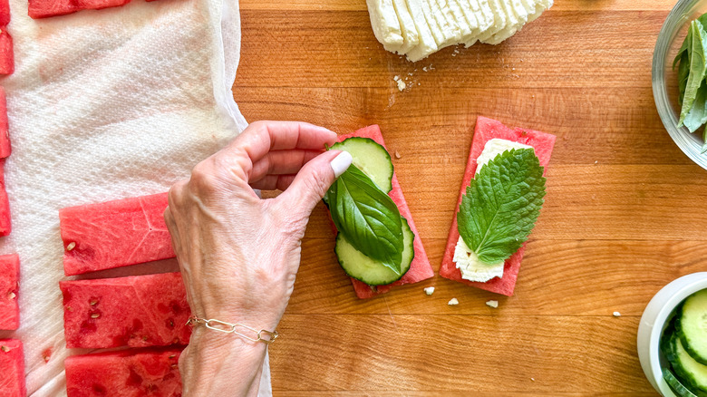 hand adding basil to sandwich