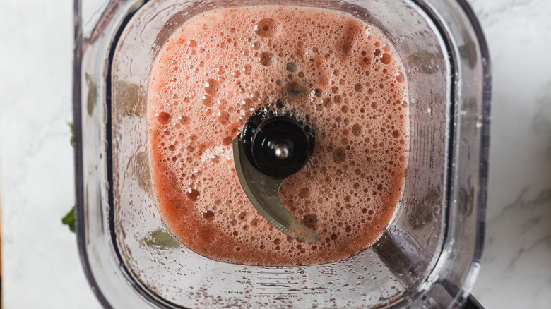 A blender with a red blended drink