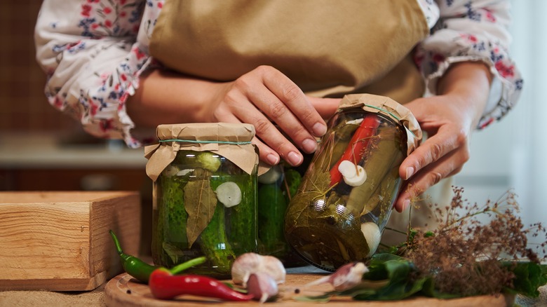 A person handling pickled jars