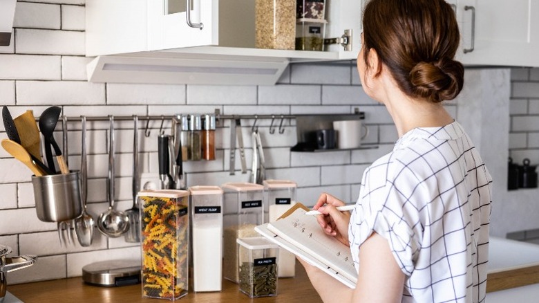 woman with notepad organizing kitchen