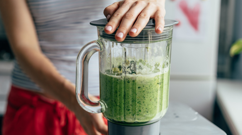 woman blending green smoothie