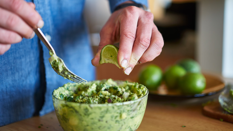 Adding lime juice to guacamole 