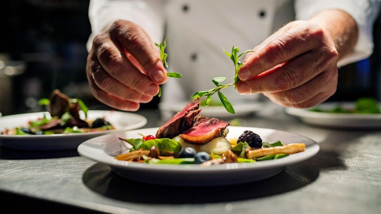 chef adding garnish to restaurant dishes