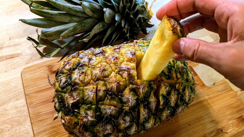 hand pulling piece from pineapple