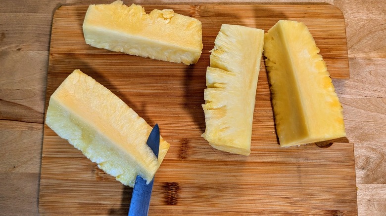 knife slicing pineapple chunk